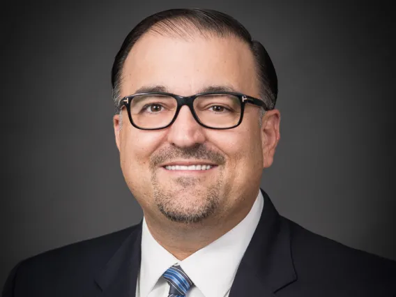 Headshot of Dimitrios in Space Grey suit with diagonal blue and grey tie